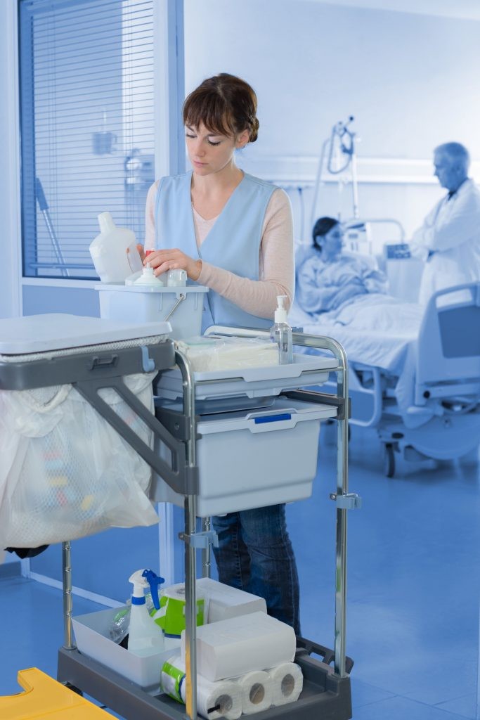 Hospital cleaner preparing her trolley on a ward